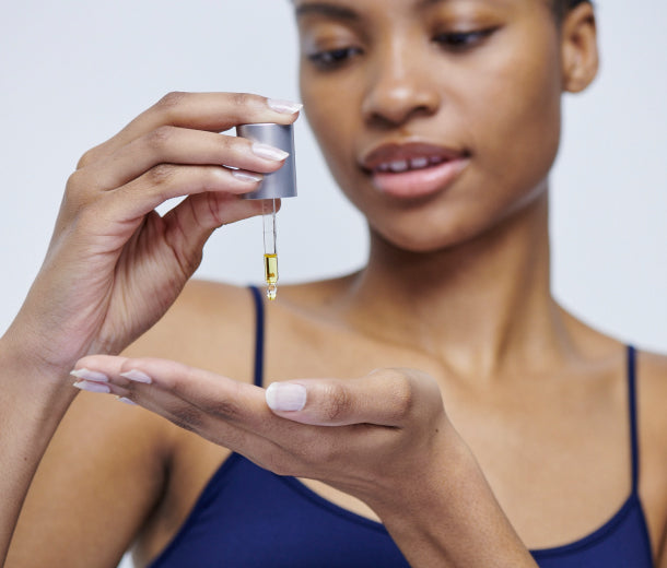Model dropping Carrot Seed Soothing Facial oil onto her hands